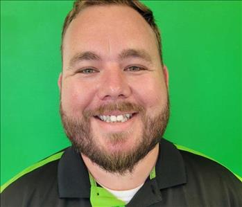 Man standing in front of a green background with SERVPRO shirt on.