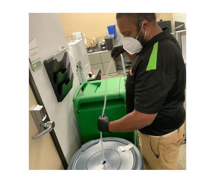 Technician collects water from a dehumidifier. 