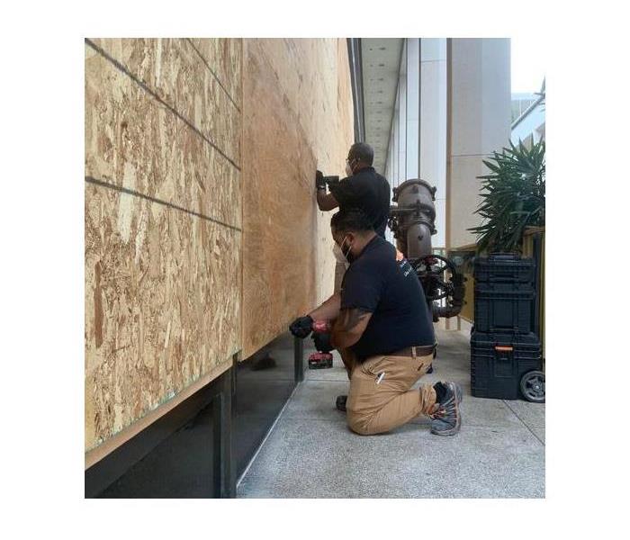 Technician boarding up broken windows.