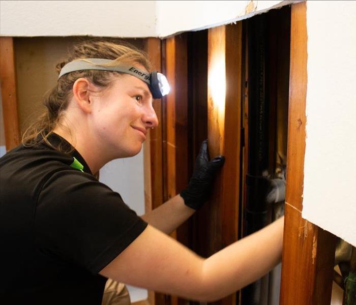 servpro technician disinfecting wall after water burst