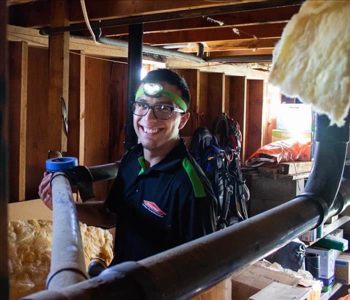 SERVPRO of San Diego East Tech wearing a light on forehead looking for water leaks in basement of home