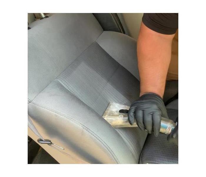 Technician cleaning car upholstery.