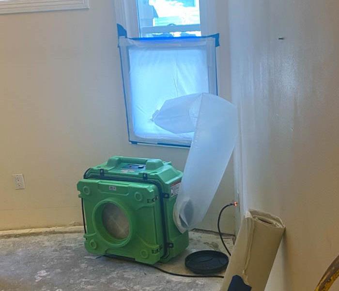 A green air scrubber on the floor of a room.